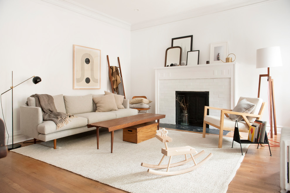 Photo of a scandinavian formal open concept living room in Los Angeles with white walls, a standard fireplace, a brick fireplace surround, brown floor, dark hardwood floors and no tv.