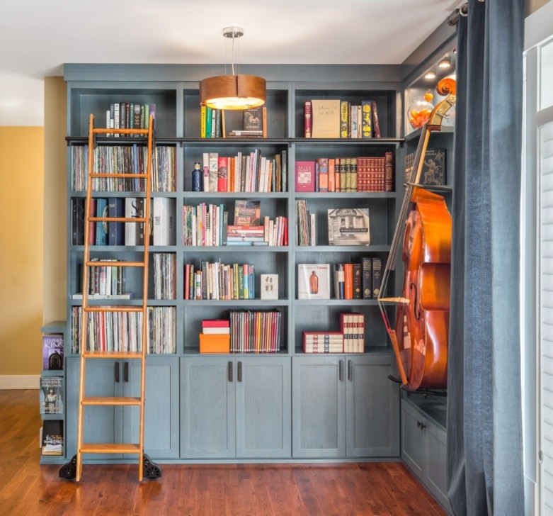 This is an example of a large transitional open concept family room in Seattle with a library, blue walls and medium hardwood floors.