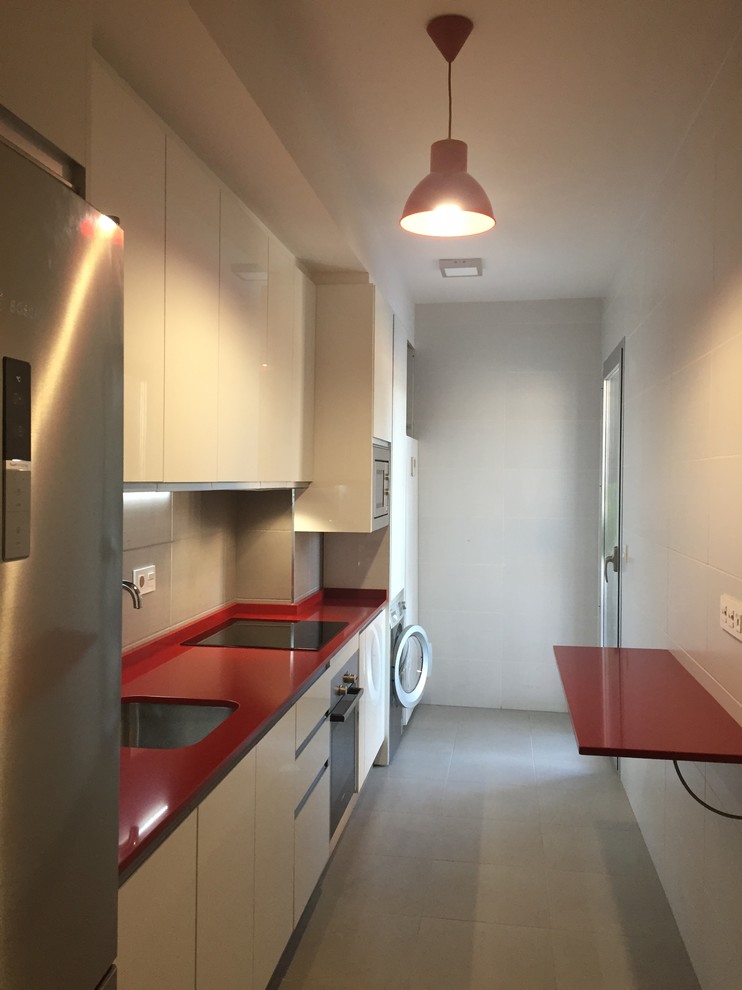 Small contemporary galley separate kitchen in Other with an undermount sink, flat-panel cabinets, white cabinets, quartz benchtops, grey splashback, ceramic splashback, stainless steel appliances and ceramic floors.
