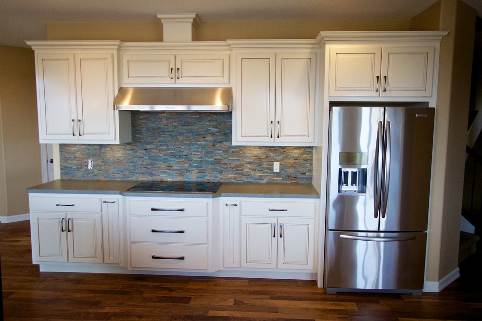 Open concept kitchen - huge open concept kitchen idea with a drop-in sink, raised-panel cabinets, white cabinets, multicolored backsplash, stone tile backsplash, stainless steel appliances and an island