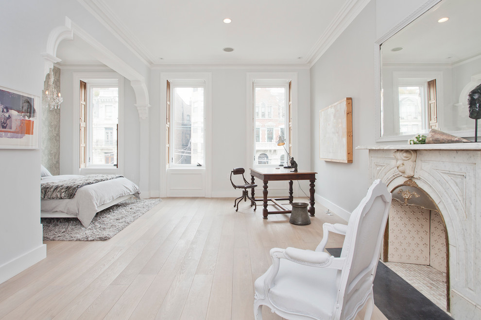 Photo of a large transitional master bedroom in New York with white walls, light hardwood floors, a standard fireplace and a stone fireplace surround.