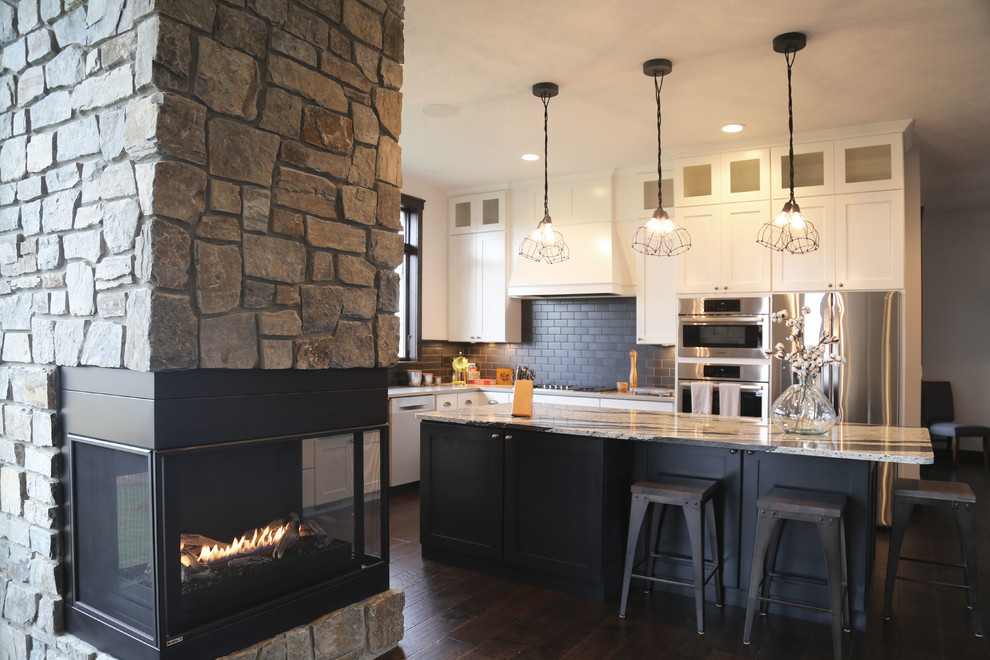 Inspiration for a mid-sized transitional l-shaped dark wood floor eat-in kitchen remodel with a farmhouse sink, recessed-panel cabinets, white cabinets, granite countertops, black backsplash, porcelain backsplash, stainless steel appliances and an island