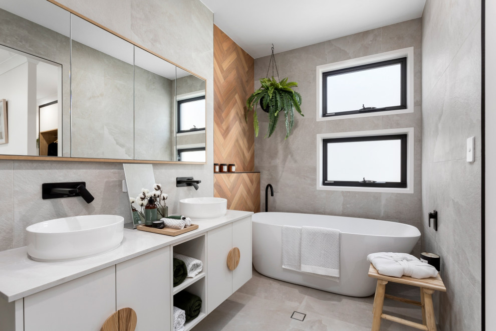 Photo of a mid-sized contemporary master bathroom in Brisbane with a freestanding tub, a corner shower, gray tile, ceramic tile, grey walls, ceramic floors, a vessel sink, grey floor, a hinged shower door, white benchtops, a double vanity and a floating vanity.