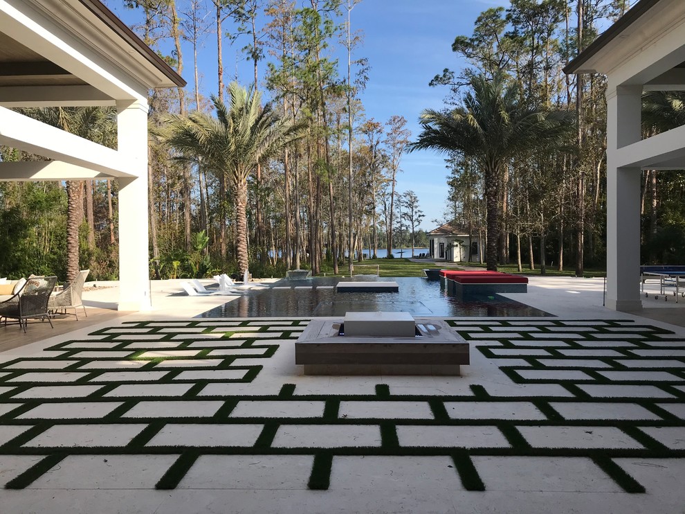 Design ideas for an expansive modern backyard custom-shaped infinity pool in Orlando with a water feature.
