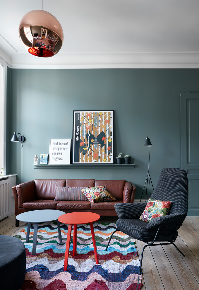 This is an example of a scandinavian living room in Copenhagen with green walls, light hardwood floors and brown floor.