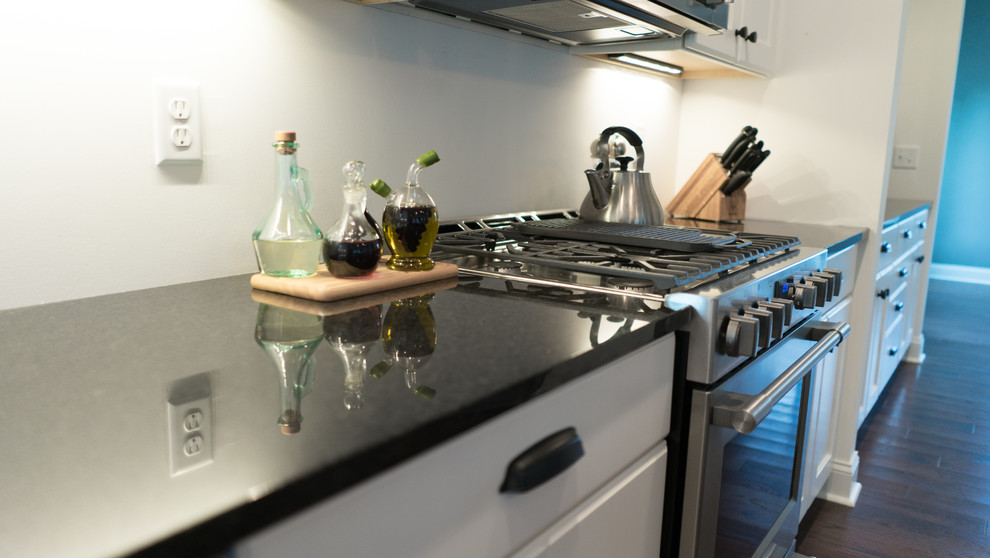 Example of a mid-sized transitional l-shaped dark wood floor open concept kitchen design with an undermount sink, shaker cabinets, white cabinets, granite countertops, gray backsplash, stainless steel appliances and an island