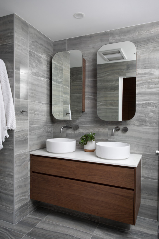 Photo of a small contemporary master bathroom in Brisbane with medium wood cabinets, a double shower, a one-piece toilet, gray tile, porcelain tile, grey walls, porcelain floors, a vessel sink, grey floor, a hinged shower door, white benchtops, a niche, a double vanity and a floating vanity.