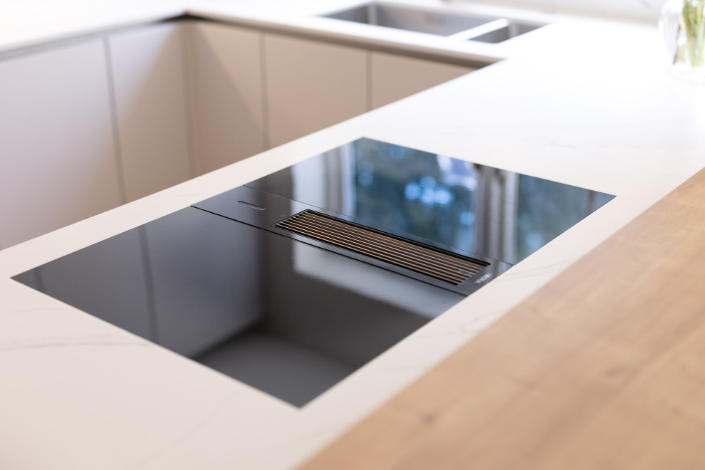 Medium sized modern u-shaped kitchen/diner in Hampshire with an integrated sink, flat-panel cabinets, grey cabinets, quartz worktops, integrated appliances, medium hardwood flooring, a breakfast bar, white worktops and feature lighting.
