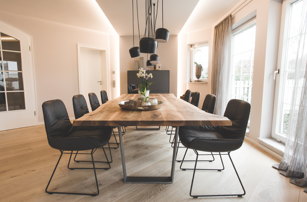 Mid-sized contemporary open plan dining in Stuttgart with light hardwood floors, white walls and beige floor.