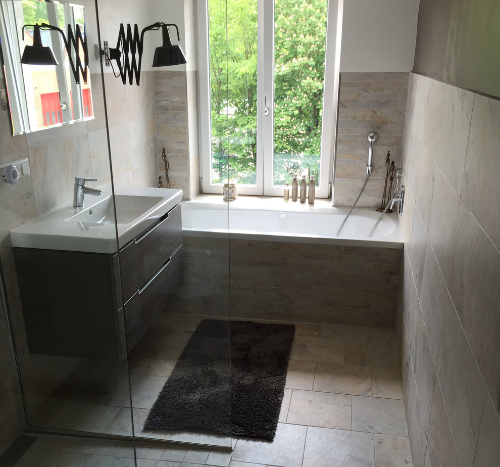 Photo of a small contemporary bathroom in Stuttgart with a drop-in tub, a curbless shower, a wall-mount toilet, multi-coloured tile, ceramic tile, multi-coloured walls, ceramic floors and a trough sink.