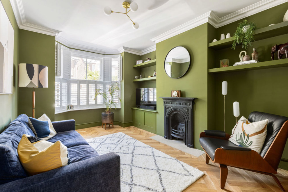 Idéer för att renovera ett mellanstort retro separat vardagsrum, med ett finrum, gröna väggar, mellanmörkt trägolv, en standard öppen spis, en spiselkrans i metall, TV i ett hörn och beiget golv