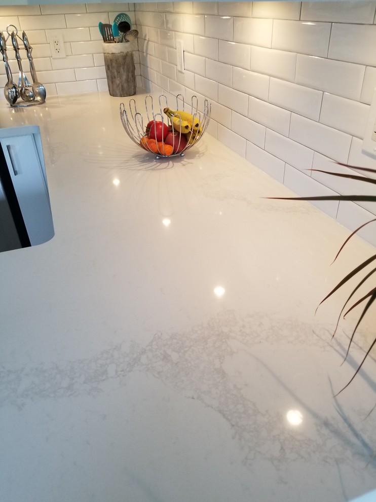 Inspiration for a small transitional u-shaped porcelain tile and beige floor eat-in kitchen remodel in Toronto with a double-bowl sink, recessed-panel cabinets, white cabinets, quartz countertops, white backsplash, subway tile backsplash, stainless steel appliances, a peninsula and white countertops