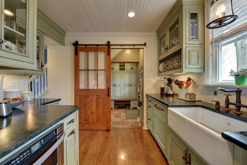 Inspiration for a small traditional galley separate kitchen in Cleveland with a farmhouse sink, beaded inset cabinets, green cabinets, soapstone benchtops, white splashback, ceramic splashback, stainless steel appliances, medium hardwood floors and no island.