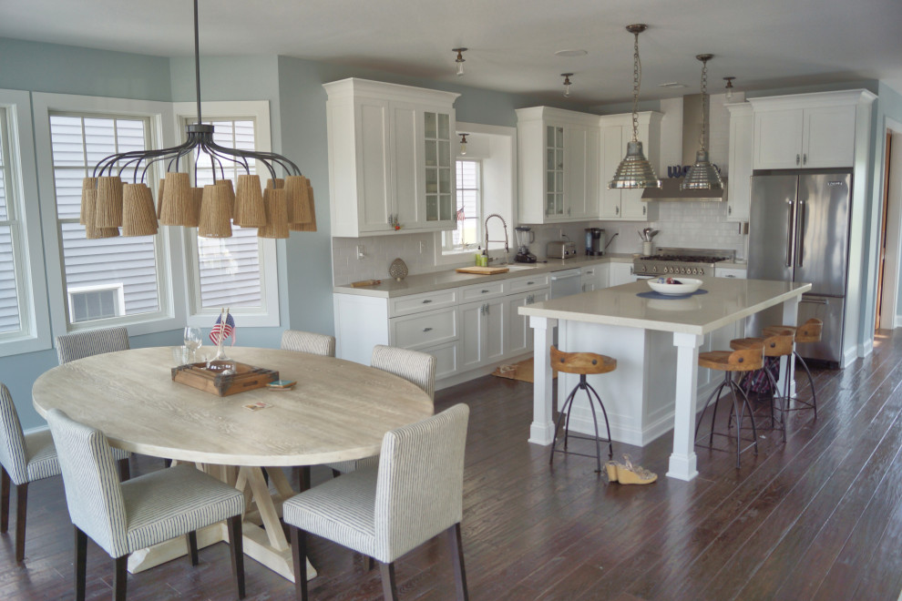 Inspiration for a small coastal l-shaped dark wood floor and brown floor open concept kitchen remodel with an undermount sink, shaker cabinets, white cabinets, quartz countertops, white backsplash, subway tile backsplash, stainless steel appliances, an island and beige countertops