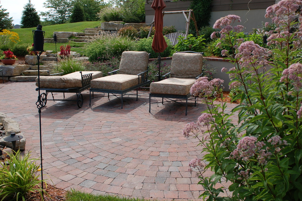 This is an example of a mid-sized traditional backyard patio in Other with brick pavers.