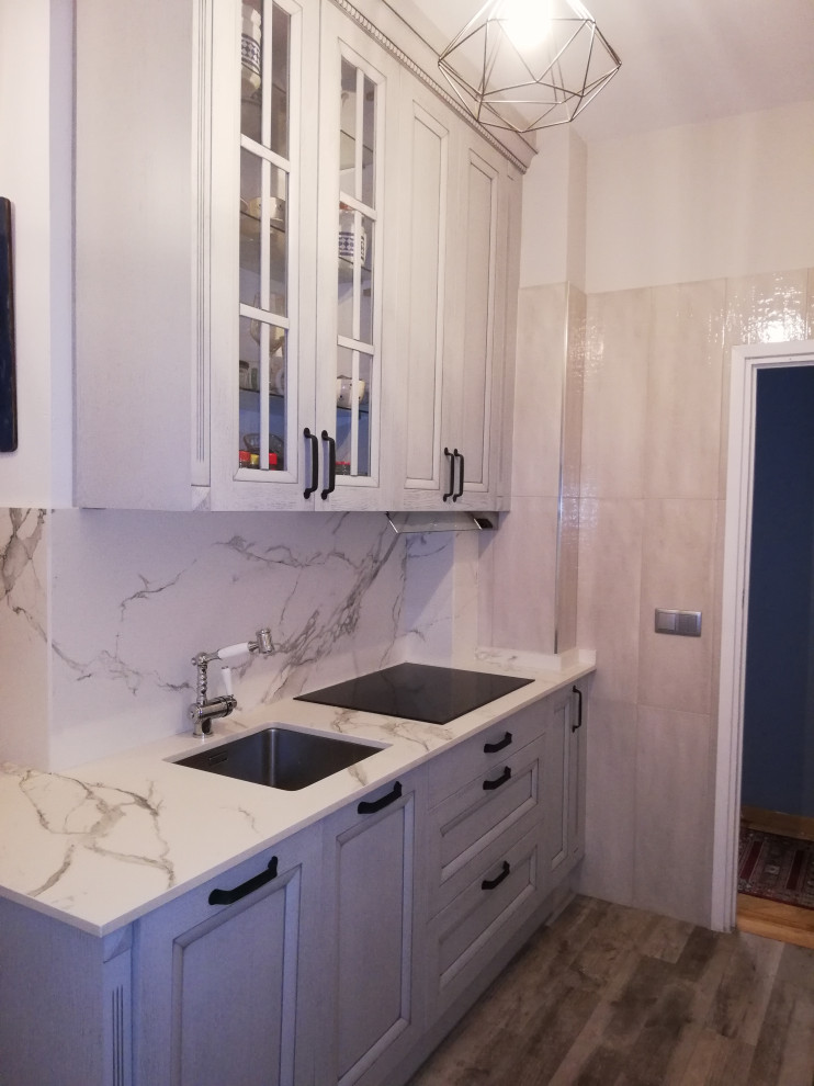 This is an example of a mid-sized transitional l-shaped separate kitchen in Madrid with an undermount sink, raised-panel cabinets, light wood cabinets, quartz benchtops, multi-coloured splashback, panelled appliances, porcelain floors, no island, multi-coloured floor and multi-coloured benchtop.