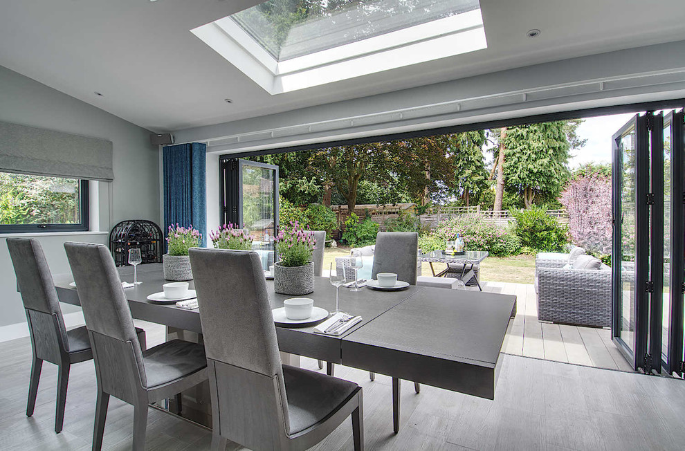 Design ideas for a large contemporary open plan dining in Hampshire with blue walls, porcelain floors and grey floor.