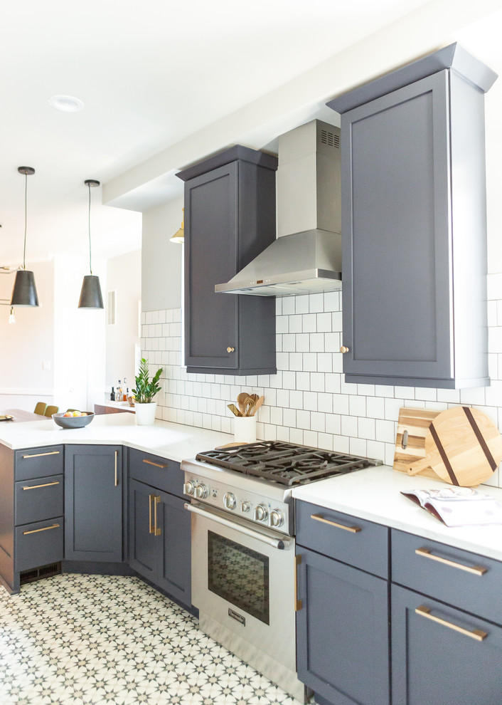 This is an example of a mid-sized midcentury u-shaped separate kitchen in DC Metro with an undermount sink, shaker cabinets, blue cabinets, marble benchtops, white splashback, subway tile splashback, stainless steel appliances, vinyl floors, a peninsula, multi-coloured floor and white benchtop.