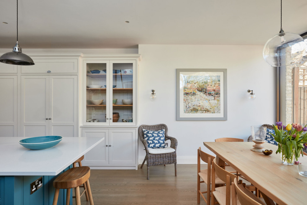 Exempel på ett mellanstort modernt vit linjärt vitt kök och matrum, med en nedsänkt diskho, skåp i shakerstil, blå skåp, bänkskiva i koppar, brunt stänkskydd, stänkskydd i tegel, integrerade vitvaror, mellanmörkt trägolv, en köksö och brunt golv