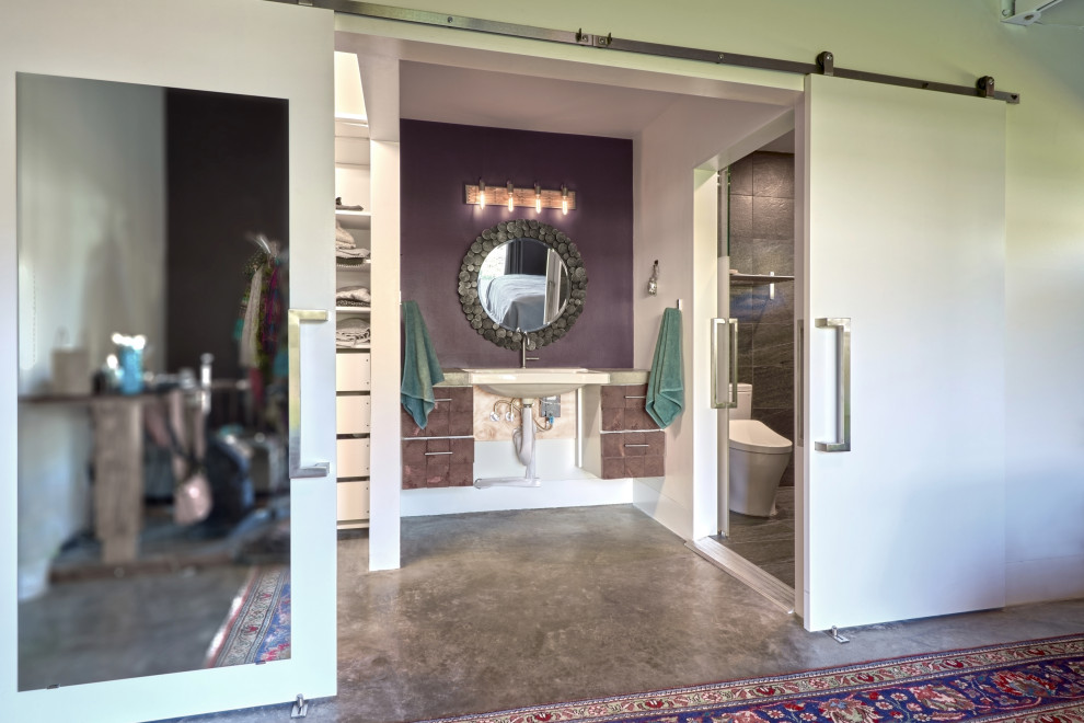 This is an example of a mid-sized eclectic master bathroom in Seattle with medium wood cabinets, a curbless shower, a one-piece toilet, purple walls, concrete floors, a wall-mount sink, concrete benchtops, grey floor, a sliding shower screen, grey benchtops, a single vanity, a floating vanity, exposed beam and panelled walls.