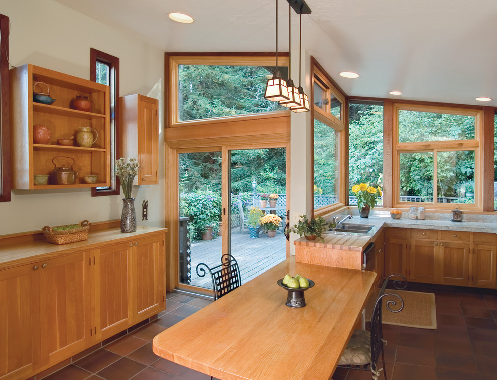 Mid-sized arts and crafts u-shaped eat-in kitchen in Other with a double-bowl sink, shaker cabinets, light wood cabinets, wood benchtops, ceramic floors, a peninsula and brown floor.