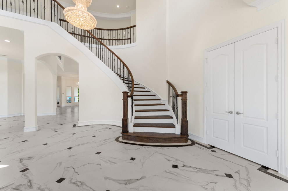 This is an example of an expansive mediterranean wood curved staircase in Dallas with wood risers and metal railing.