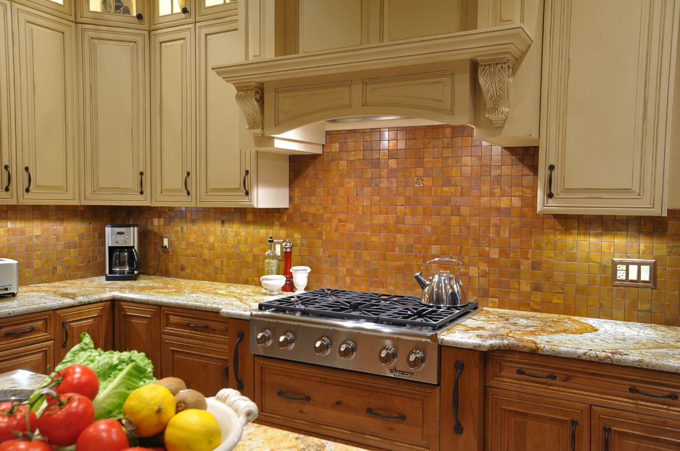 Inspiration for a transitional ceramic tile kitchen remodel with an undermount sink, raised-panel cabinets, distressed cabinets, granite countertops, metallic backsplash, metal backsplash, paneled appliances and an island