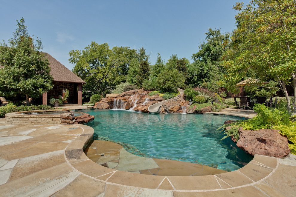 This is an example of a traditional custom-shaped natural pool in Dallas with a water slide.