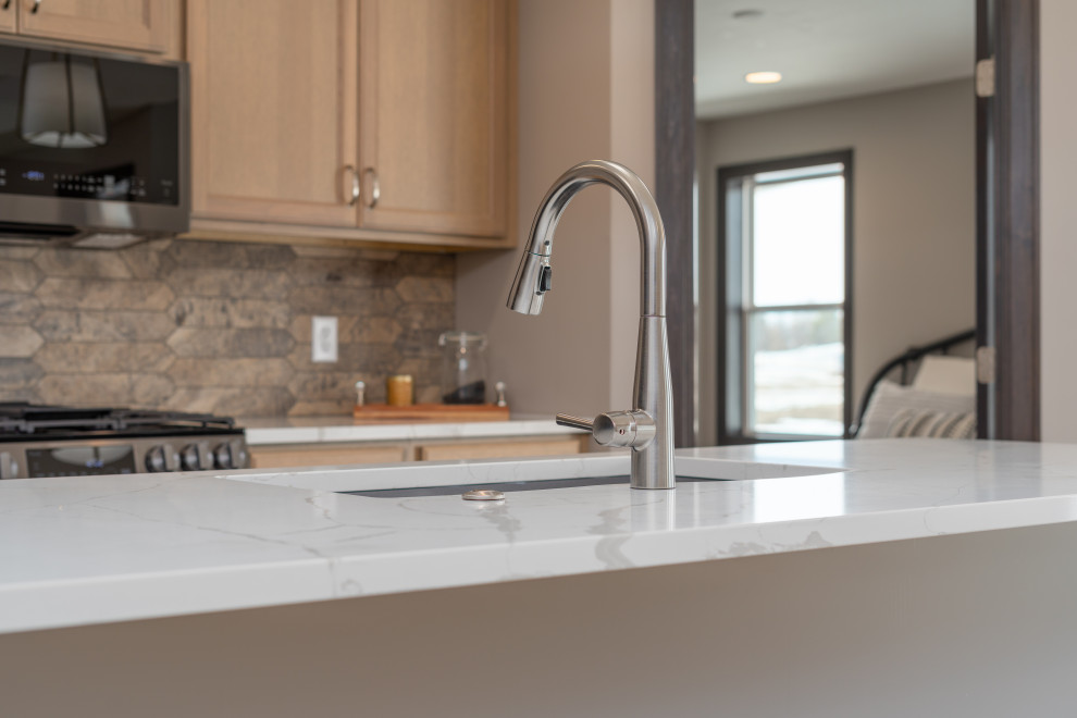Eat-in kitchen - transitional l-shaped eat-in kitchen idea with an undermount sink, shaker cabinets, light wood cabinets, quartz countertops, beige backsplash, black appliances, an island and white countertops