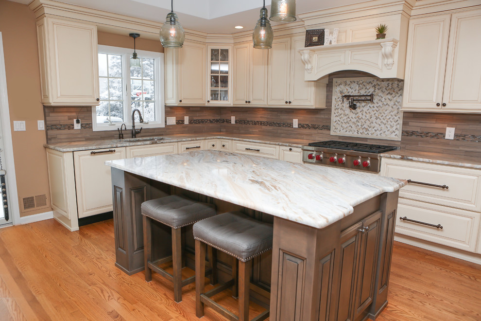 Example of a large transitional u-shaped light wood floor eat-in kitchen design in Newark with an undermount sink, raised-panel cabinets, distressed cabinets, granite countertops, brown backsplash, mosaic tile backsplash, stainless steel appliances and an island