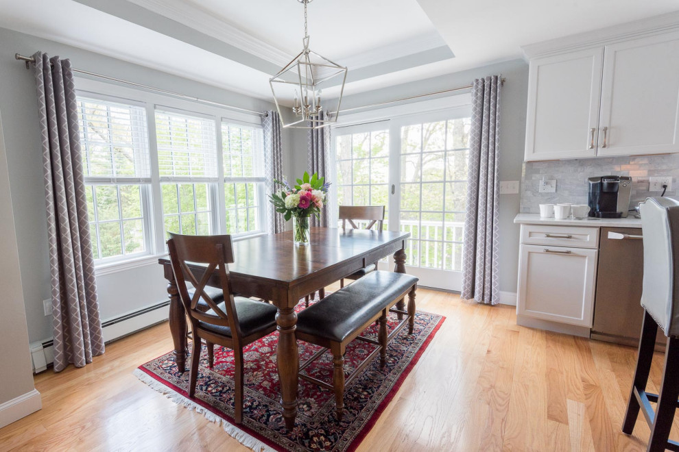 Eat-in kitchen - large transitional l-shaped medium tone wood floor, brown floor and coffered ceiling eat-in kitchen idea in Boston with an undermount sink, shaker cabinets, white cabinets, quartz countertops, gray backsplash, subway tile backsplash, stainless steel appliances, an island and white countertops