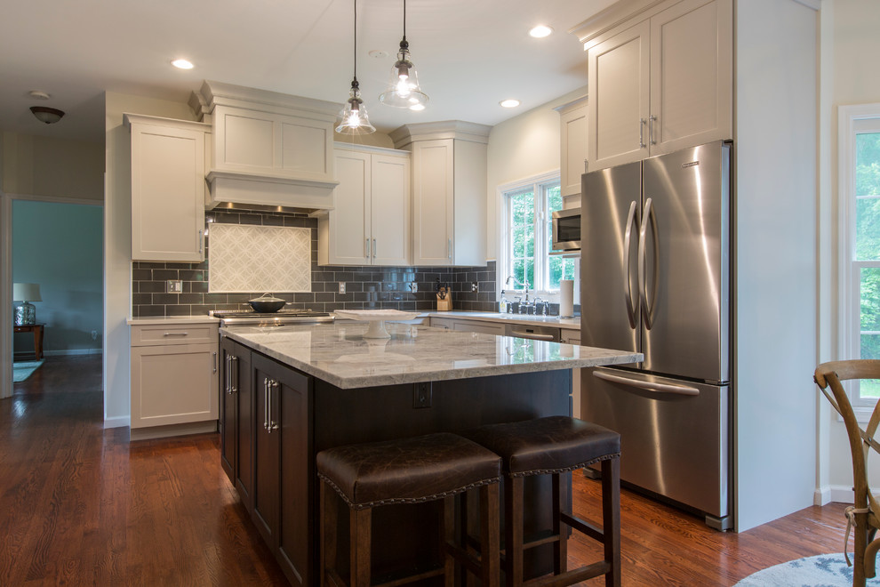Photo of a mid-sized transitional l-shaped eat-in kitchen in Bridgeport with an undermount sink, recessed-panel cabinets, grey cabinets, granite benchtops, black splashback, ceramic splashback, stainless steel appliances, medium hardwood floors and with island.