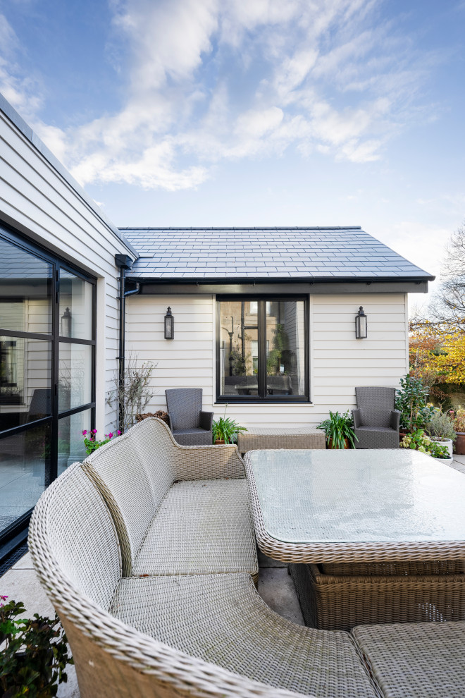 Inspiration pour une façade de maison grise design en bois de taille moyenne et de plain-pied avec un toit plat et un toit bleu.