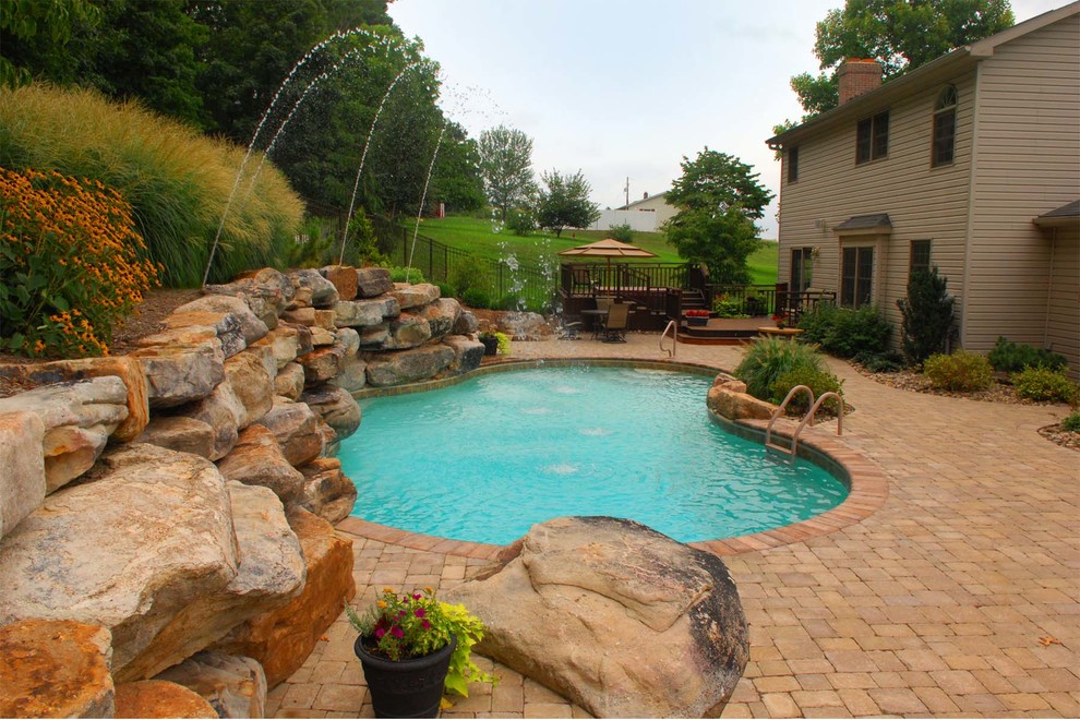 Mid-sized mediterranean backyard custom-shaped lap pool in Other with a water feature and concrete pavers.