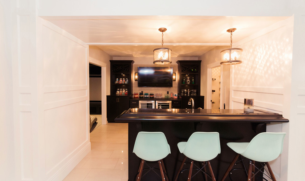 Inspiration for a mid-sized transitional galley seated home bar in Edmonton with a drop-in sink, shaker cabinets, dark wood cabinets, granite benchtops, beige splashback, ceramic splashback and ceramic floors.