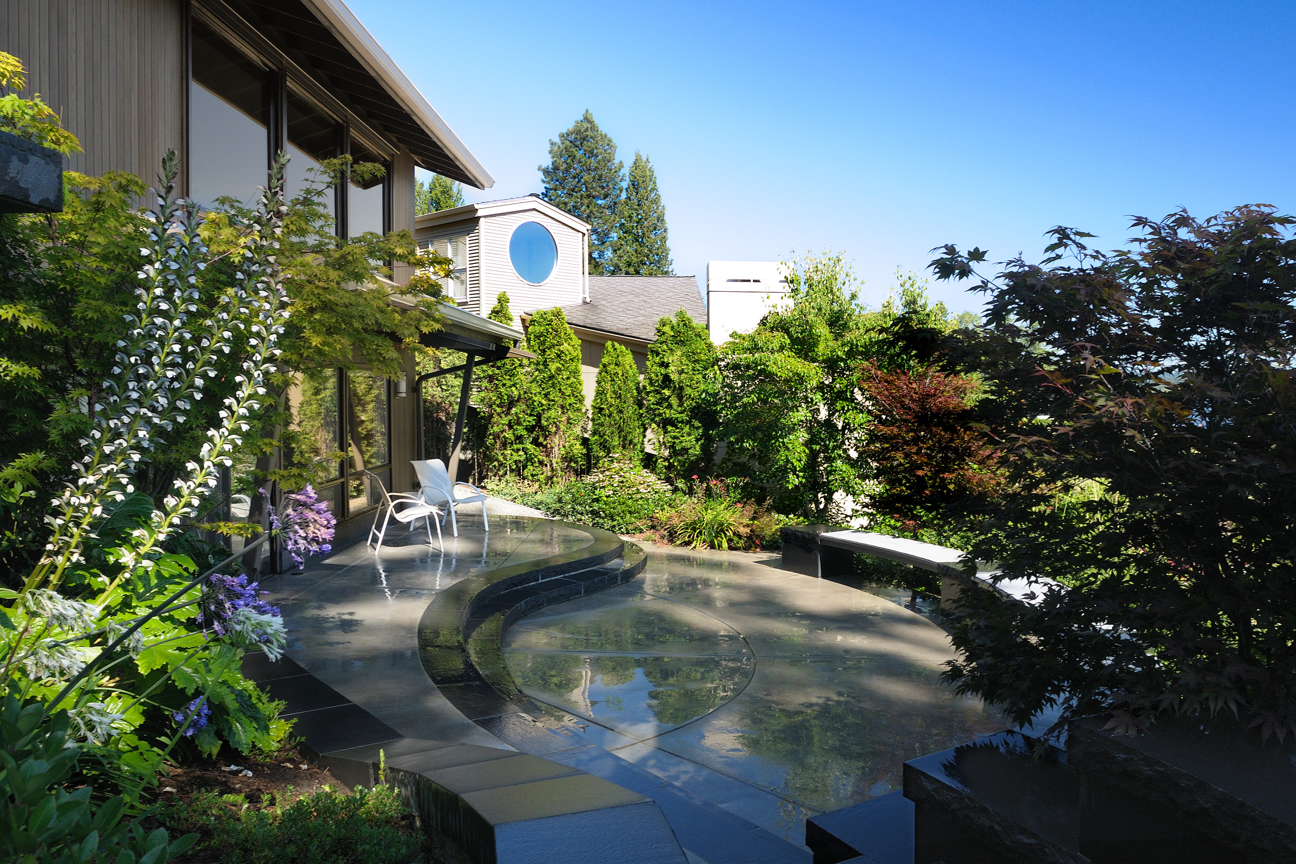 Rear patio with curvilinear stone steps and bench