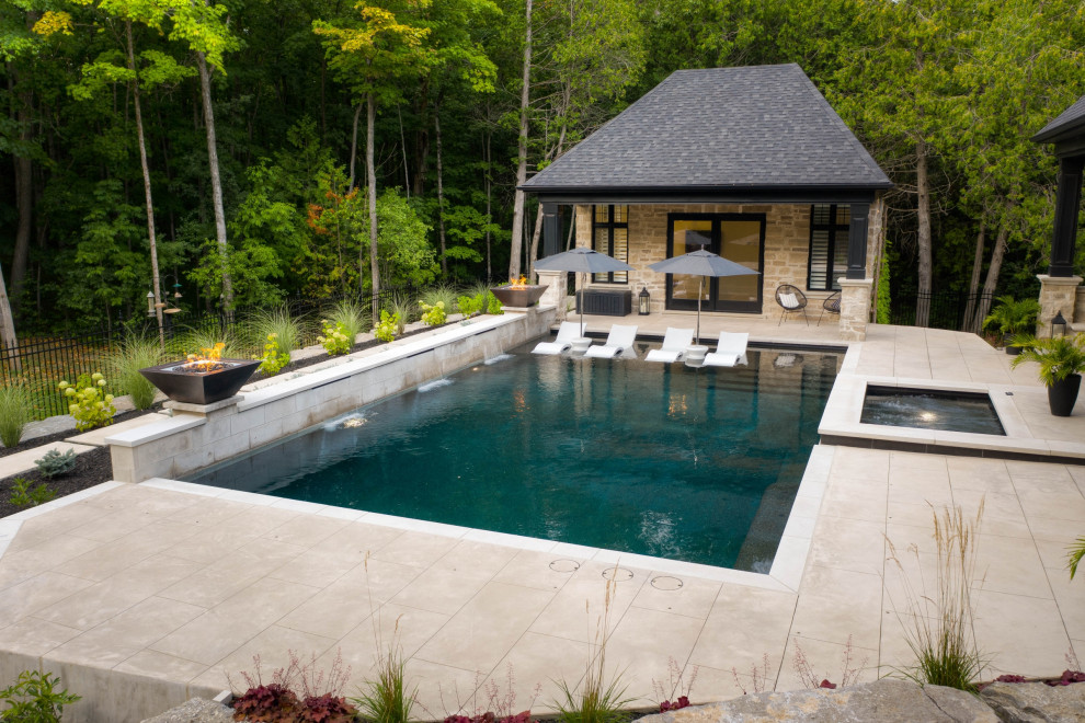 Cette photo montre un piscine avec aménagement paysager arrière chic de taille moyenne et rectangle avec du béton estampé.