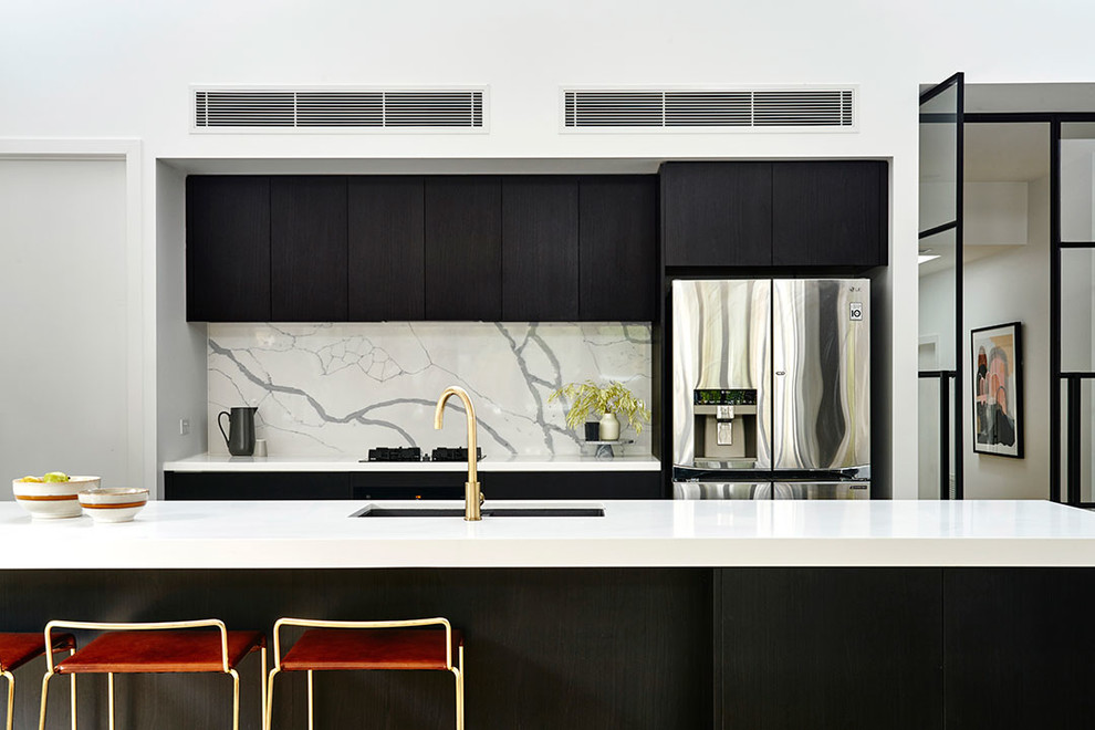Inspiration for a modern galley eat-in kitchen in Geelong with an undermount sink, black cabinets, quartzite benchtops, marble splashback, black appliances, concrete floors, with island, grey floor and white benchtop.