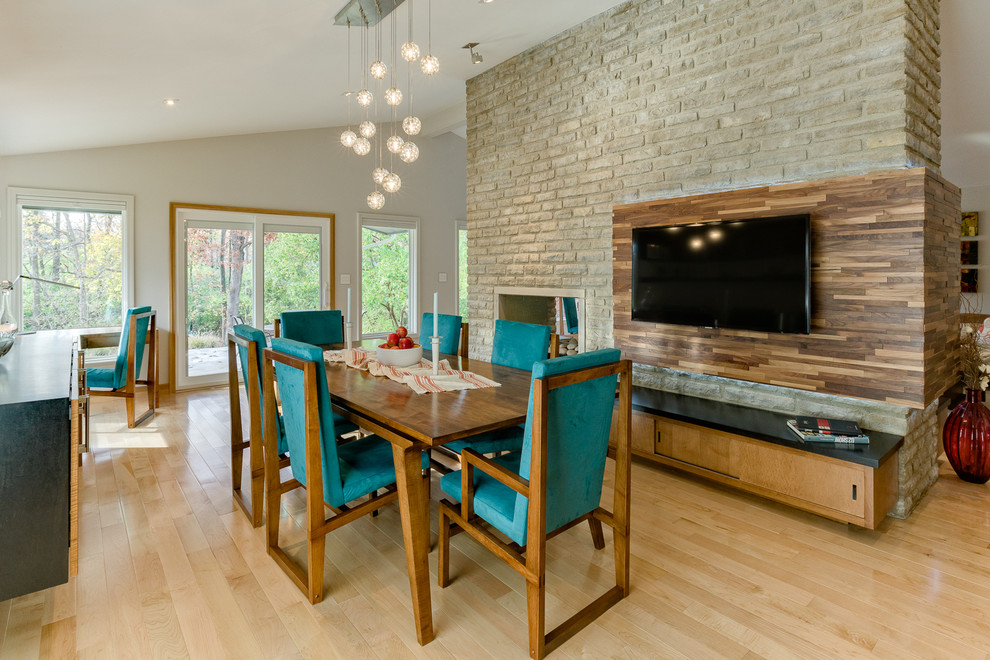 Photo of a mid-sized modern separate dining room in Columbus with white walls, light hardwood floors, a two-sided fireplace and a stone fireplace surround.