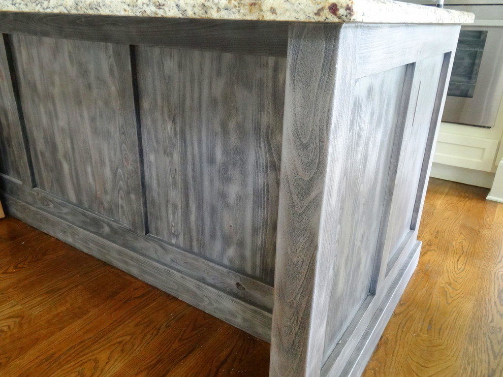 Open concept kitchen - mid-sized transitional l-shaped medium tone wood floor open concept kitchen idea in Charlotte with a farmhouse sink, shaker cabinets, white cabinets, granite countertops, beige backsplash, subway tile backsplash, stainless steel appliances and an island