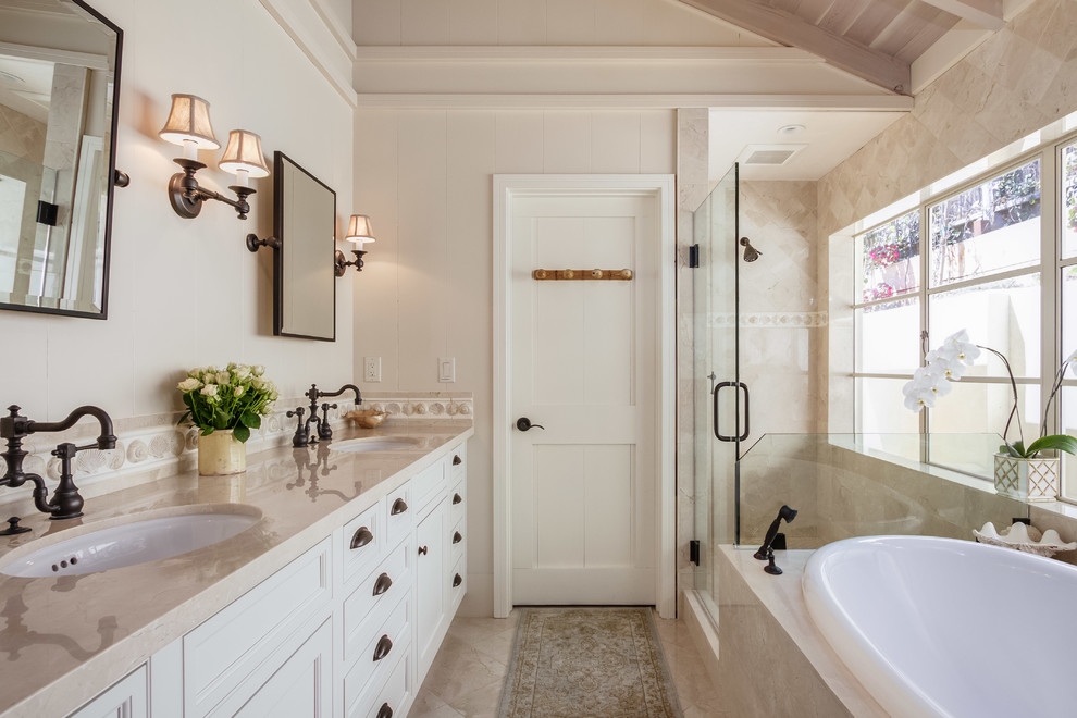 Design ideas for a mid-sized transitional master bathroom in San Francisco with a drop-in tub, beige walls, marble floors, an undermount sink, marble benchtops, beige floor, beige benchtops, recessed-panel cabinets, white cabinets, a shower/bathtub combo and a hinged shower door.