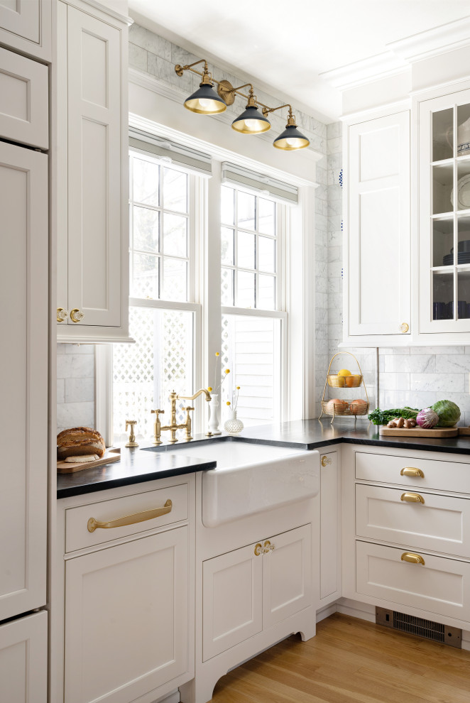 Inspiration for a l-shaped eat-in kitchen remodel in Wilmington with white cabinets, paneled appliances, black countertops, a farmhouse sink, soapstone countertops, white backsplash and an island