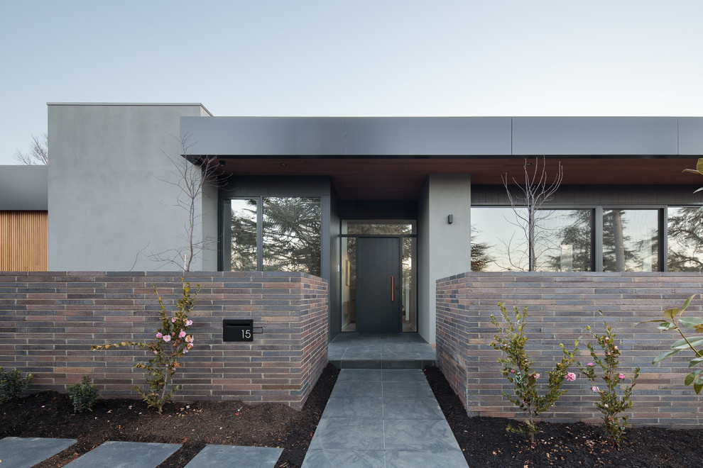 This is an example of a contemporary front door in Canberra - Queanbeyan with a single front door, a black front door and grey floor.