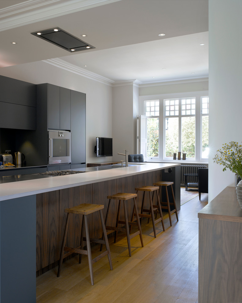 Inspiration for a large contemporary open plan kitchen in London with an undermount sink, flat-panel cabinets, blue cabinets, solid surface benchtops and with island.