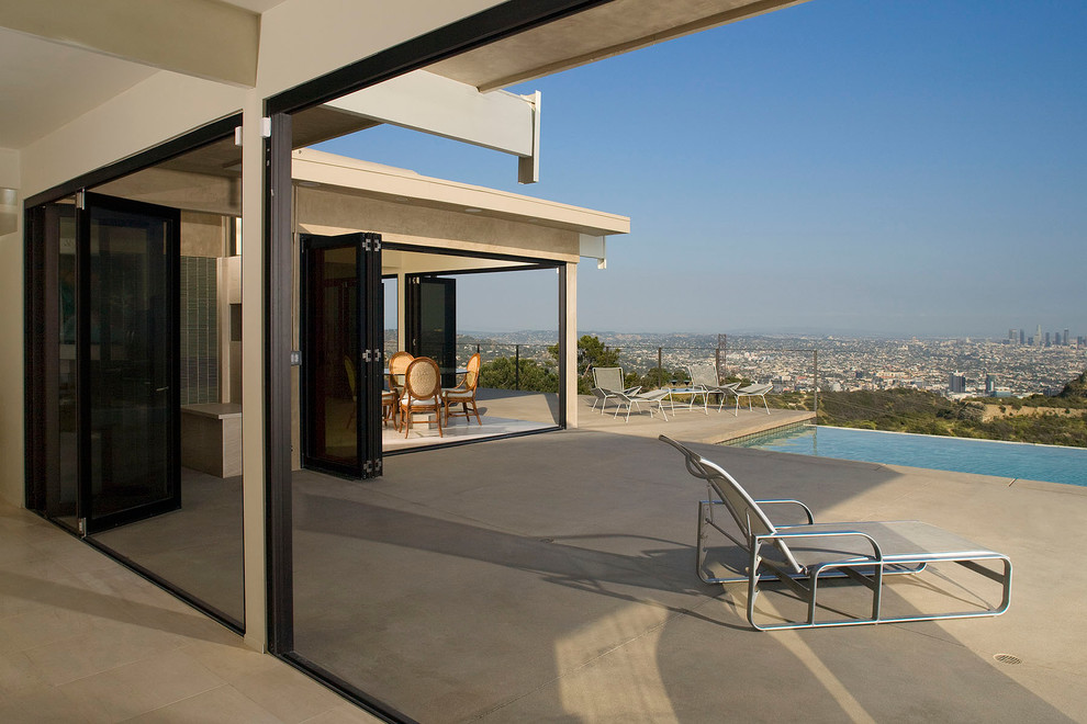 Inspiration for a large contemporary rooftop l-shaped infinity pool in Orange County with concrete pavers.