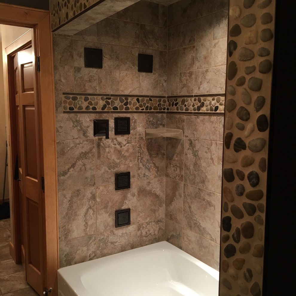 This is an example of a traditional bathroom in Other with an alcove tub, a shower/bathtub combo, brown tile, pebble tile and brown walls.