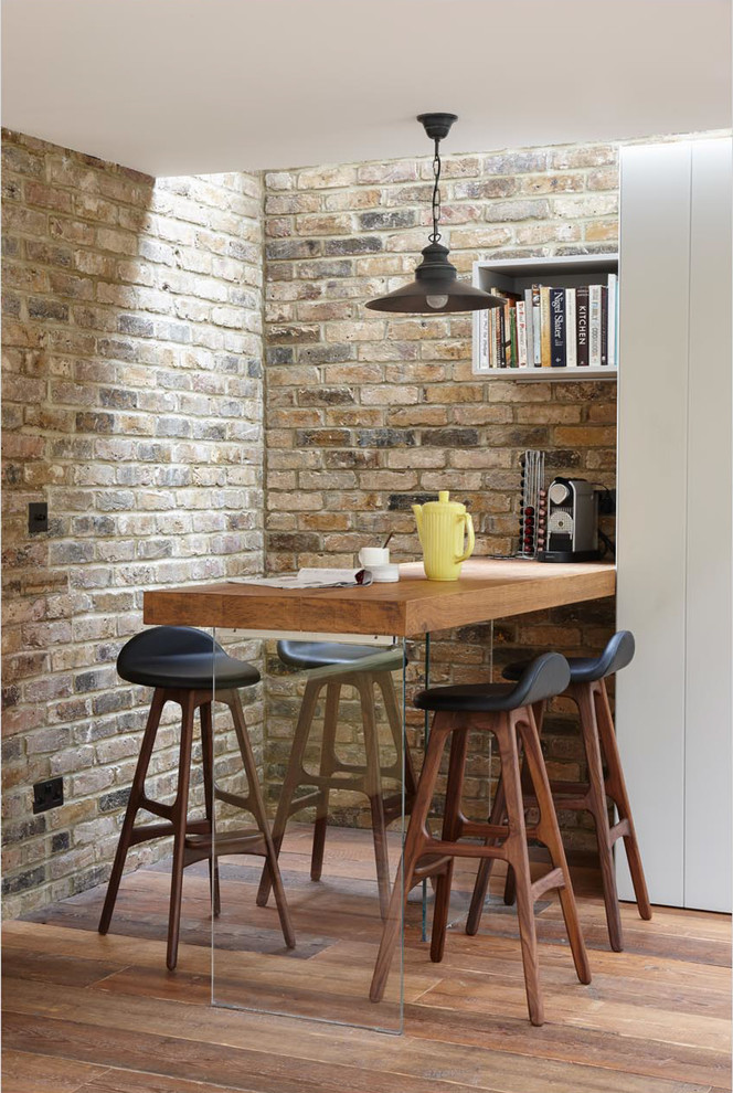 Photo of an industrial dining room in London with medium hardwood floors.
