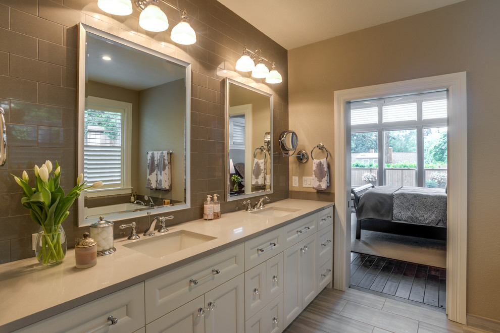 This is an example of a transitional master bathroom in Portland with recessed-panel cabinets, white cabinets, gray tile, porcelain tile, porcelain floors, an undermount sink and solid surface benchtops.