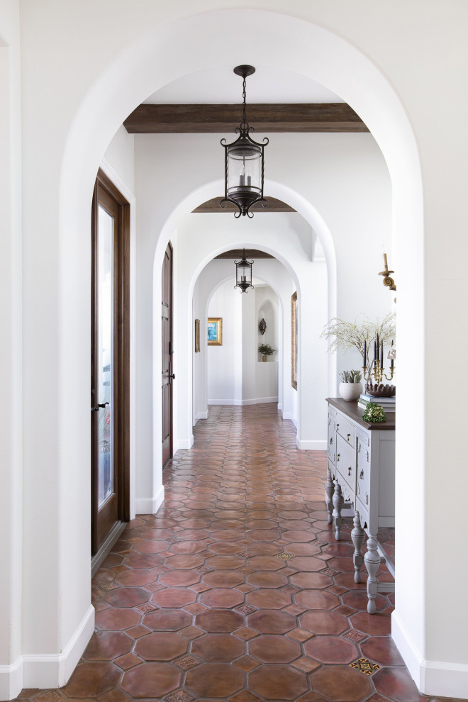 Идея дизайна: большой коридор в средиземноморском стиле с белыми стенами, полом из терракотовой плитки, коричневым полом и балками на потолке