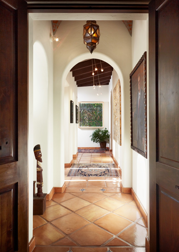 Photo of a mediterranean hallway in Austin with white walls and terra-cotta floors.
